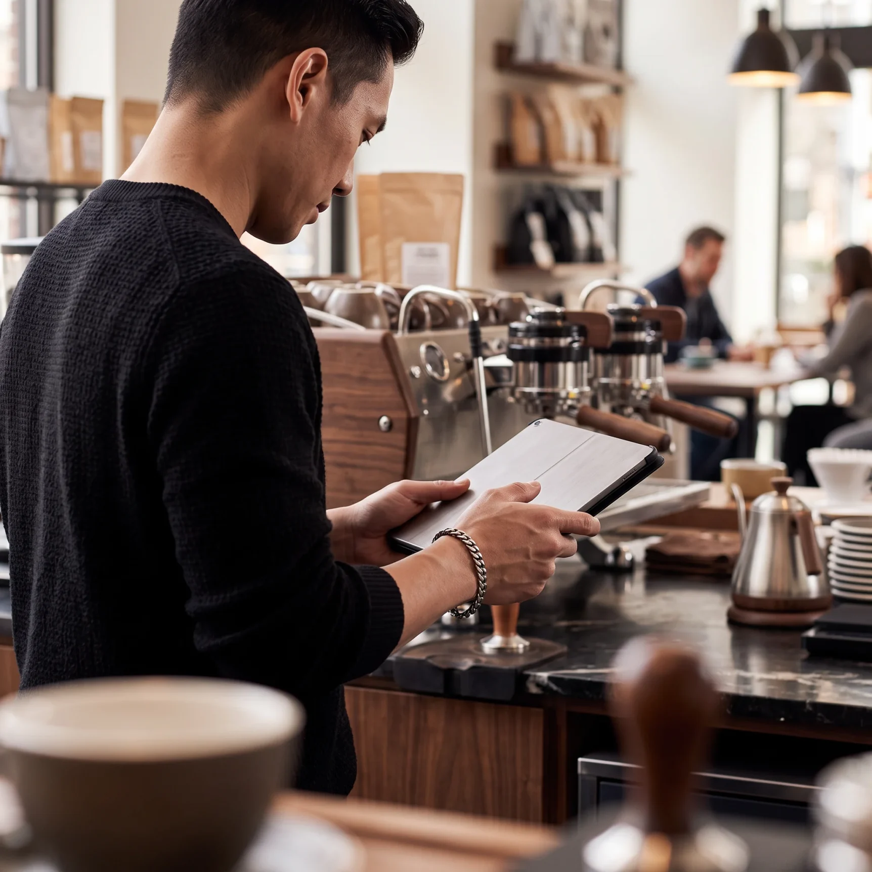 Cafe operator reviewing figures beside an espresso machine
