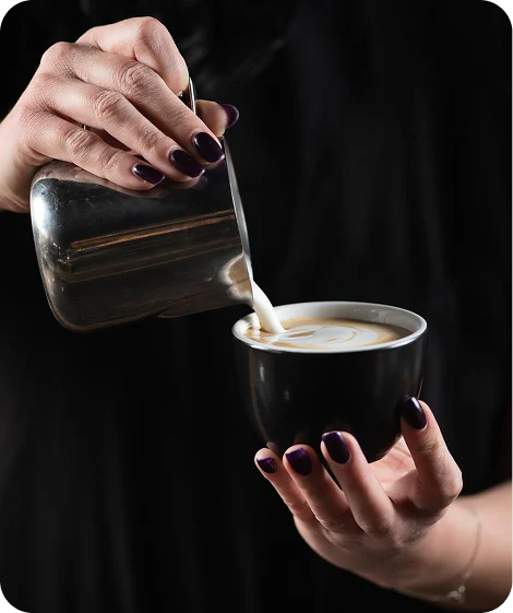 Barista pouring latte art into a cup