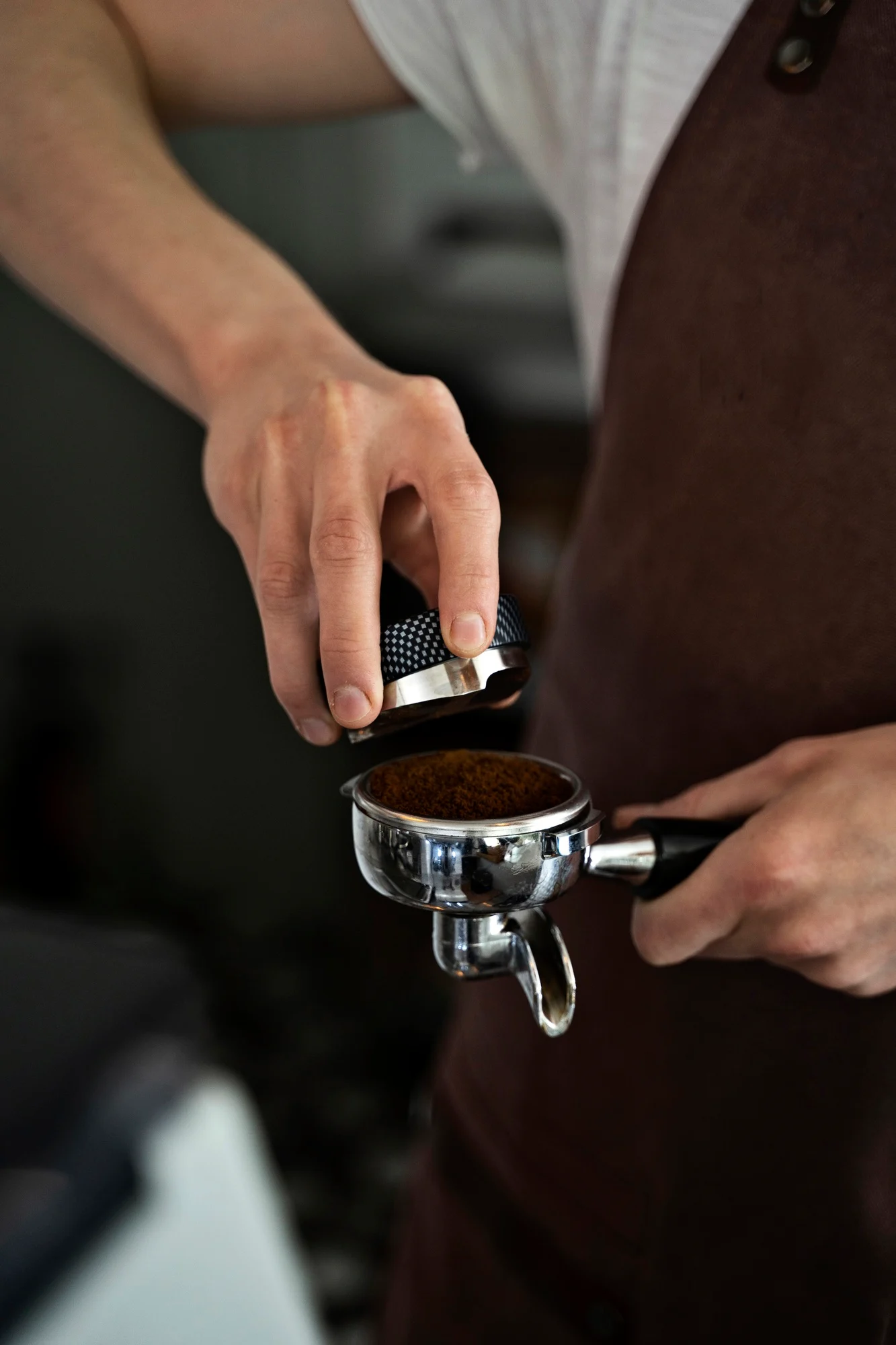 Barista tamping freshly ground coffee into a portafilter